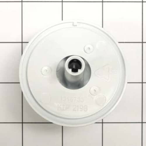 The rear view of the white dryer timer knob showing the central mounting hub with a black D-shaped coupling, set against a white grid.