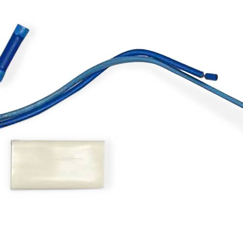 Close-up of the metal-cased thermostat with its wires and included components resting on a blue surface.