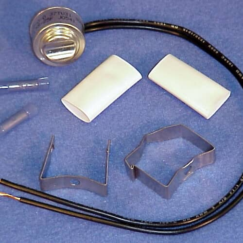 Disassembled view of the defrost thermostat, thermal fuse, wire leads, and mounting brackets.